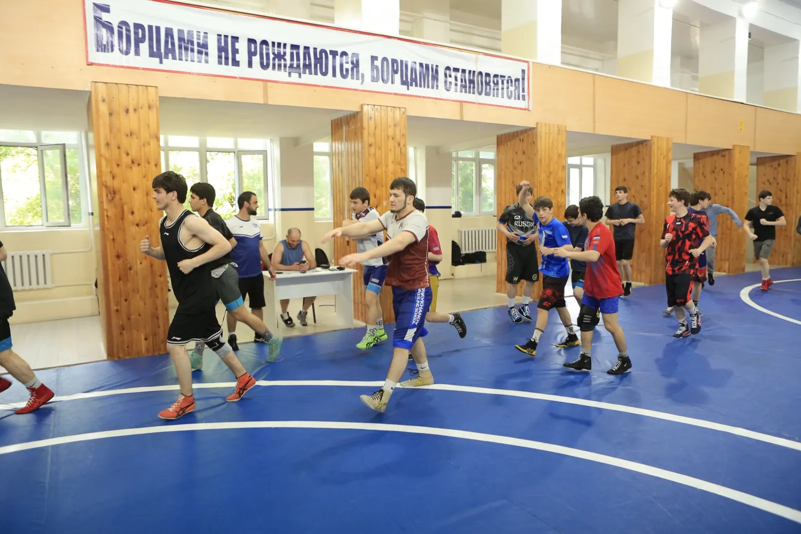 Makhachkala wrestling gym with its traditional banner, wrestlers warming up