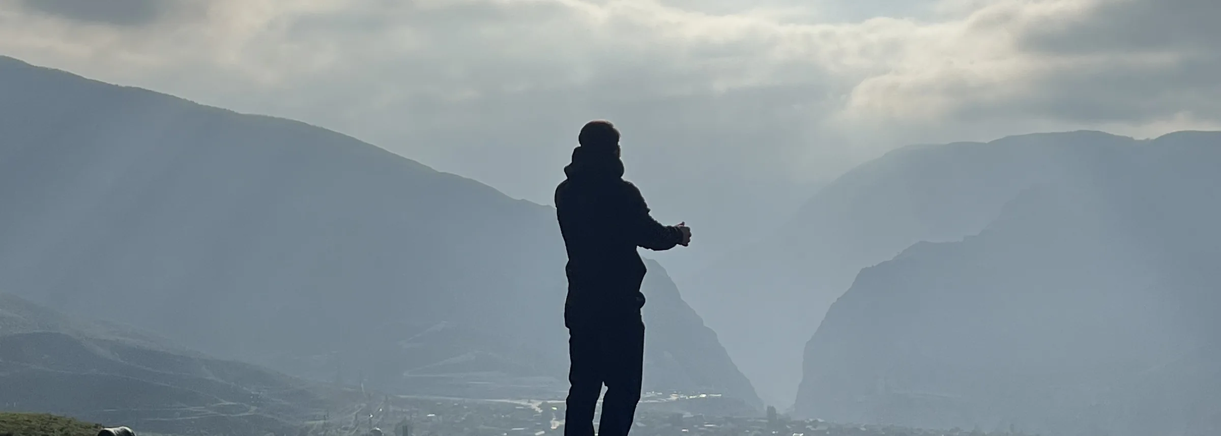 Mountains of Dagestan in the mist at sunset, the silhouette of a man facing the valley
