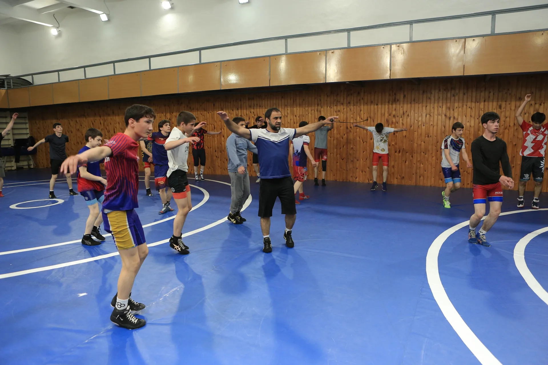 Dagestani coach leading the collective warm-up in the middle of the mat