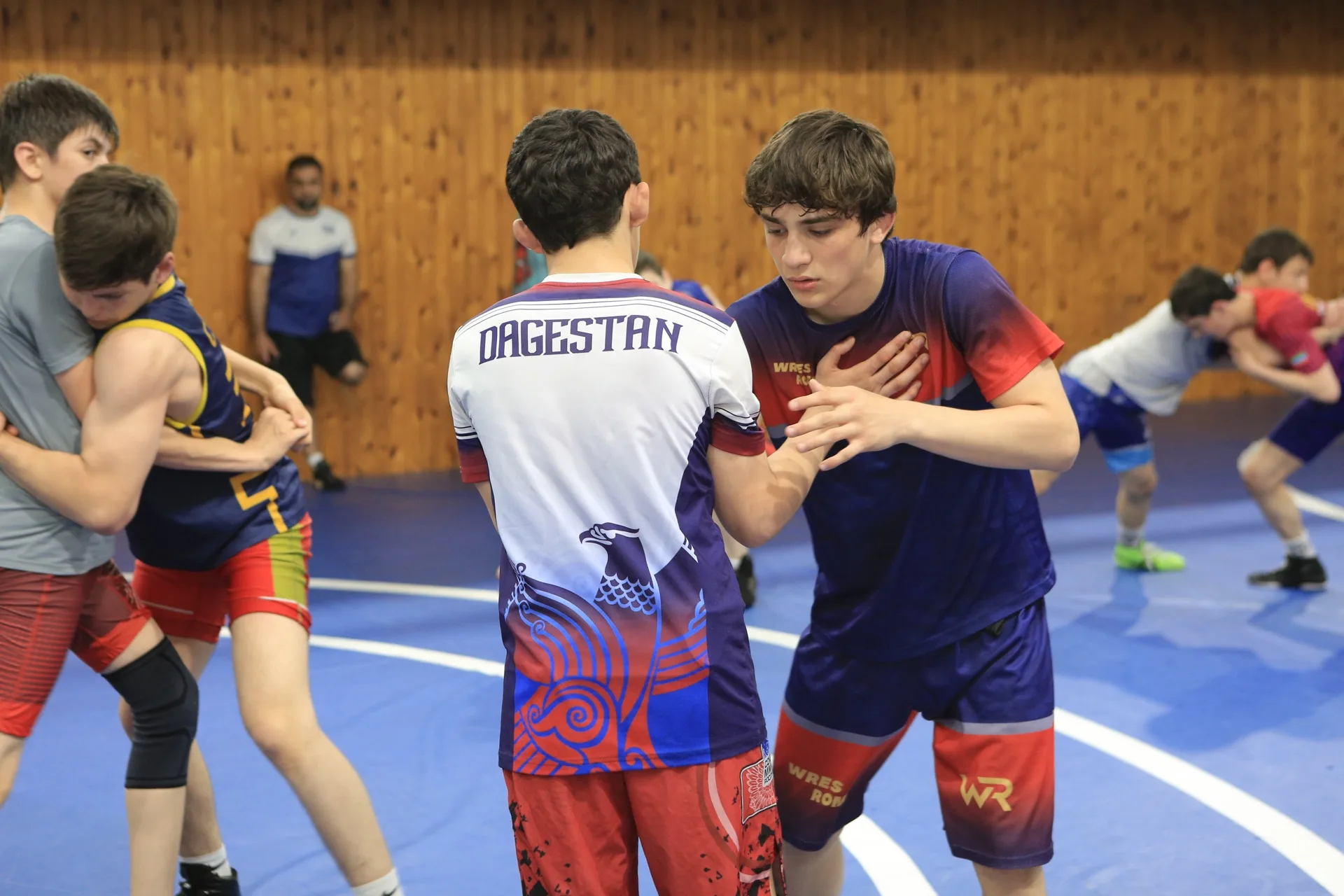 Two wrestlers drilling a clinch position, Dagestan singlet, wrestling room
