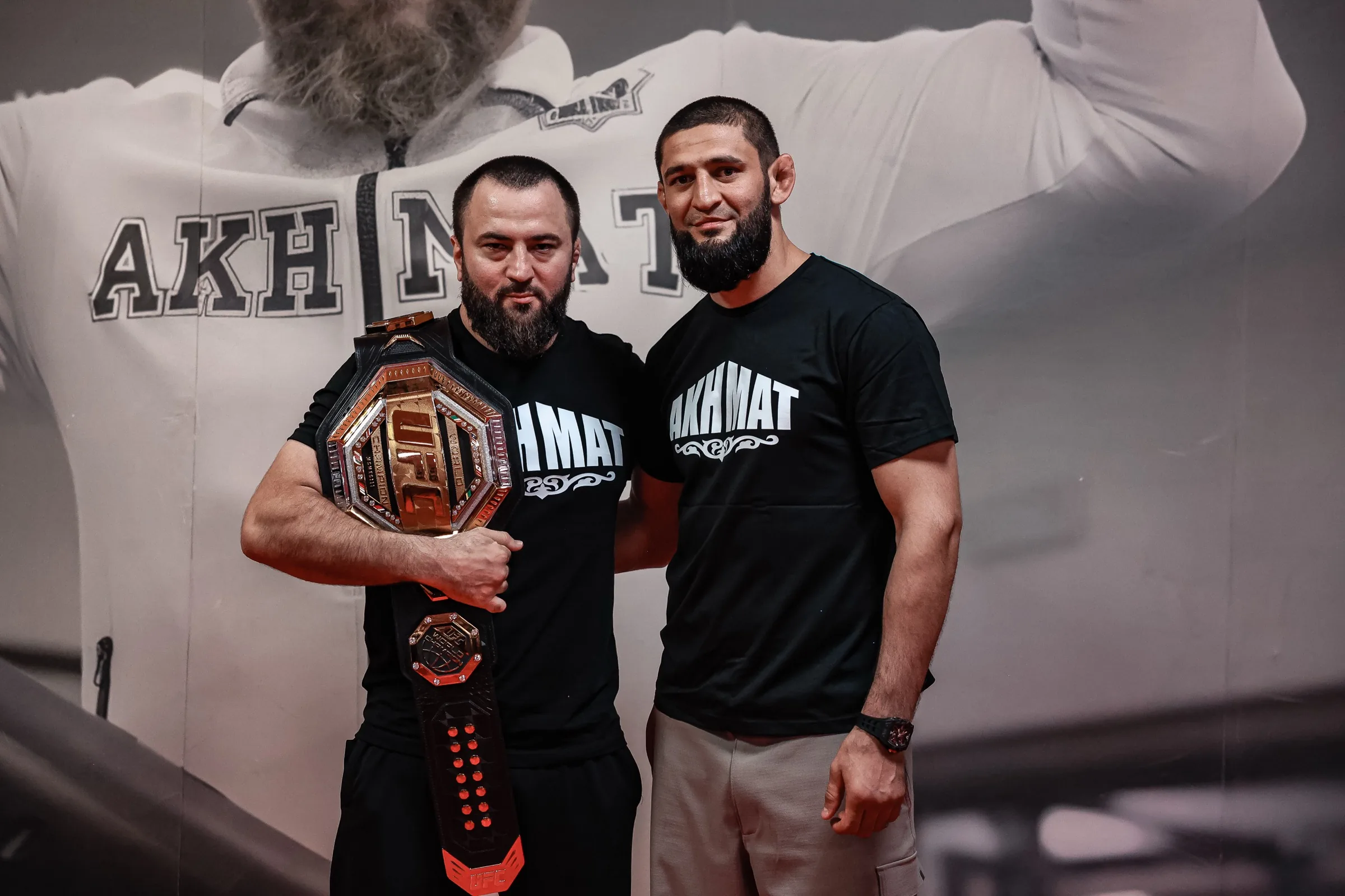 Khamzat Chimaev, ancien champion UFC poids moyens, dans la salle Akhmat Fight Club de Grozny avec un coach tenant une ceinture UFC