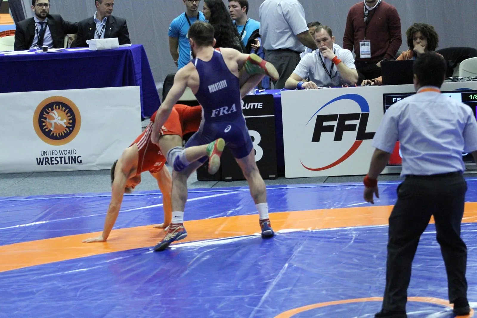 Ruslan Mukhtarov en pleine action de takedown lors d'un championnat de France de lutte, singlet bleu FRA LUTTE